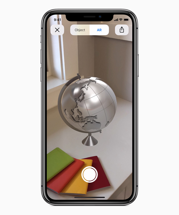 iPhone X showing an AR globe on a desk.