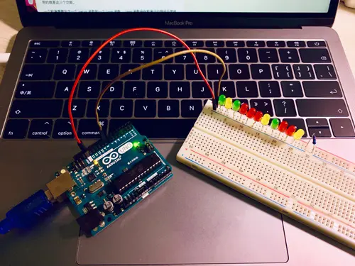 一组LED灯插在面包板上杜邦线连接Arduino开发板通过编程线连接电脑