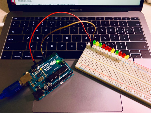 一组LED灯插在面包板上杜邦线连接Arduino开发板通过编程线连接电脑